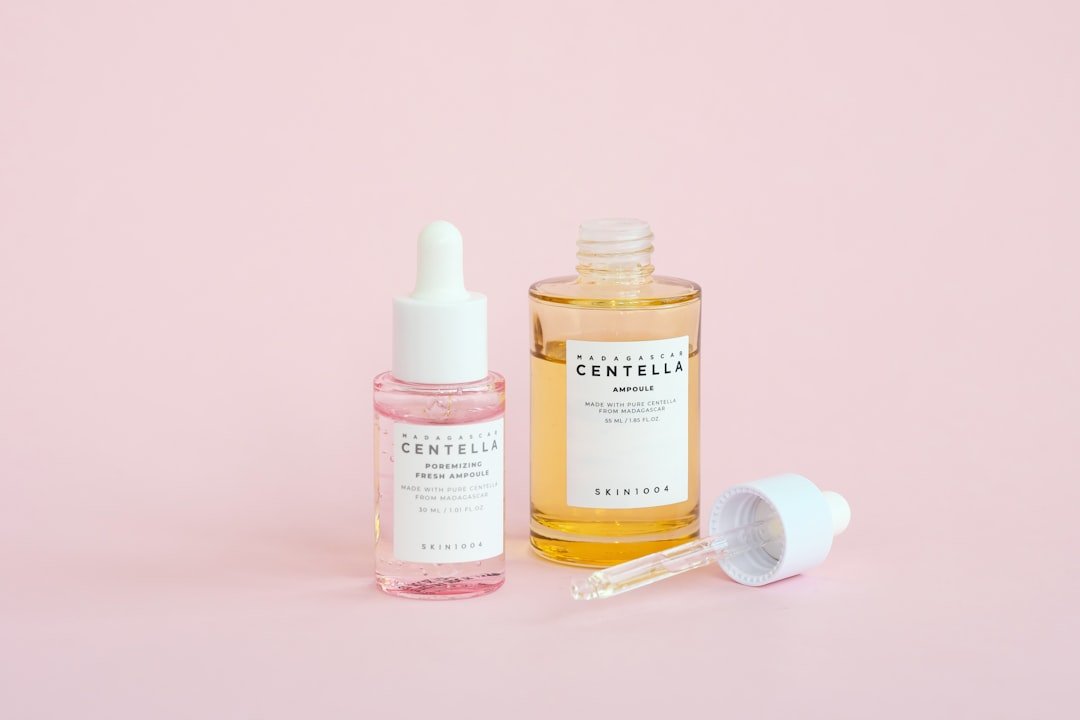 Skincare serums are displayed on a pink background