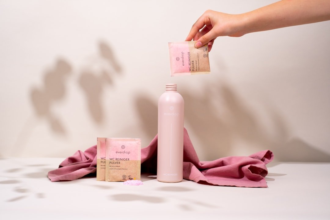 a person holding a pink bottle next to a pink towel