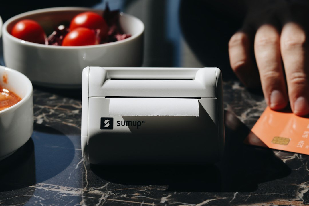 A shopper holds a bank card beside a checkout payment terminal